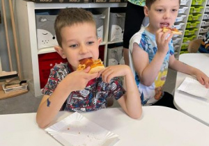Chłopcy jedzą pizzę